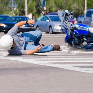 A man lying on the ground next to a motorcycle involved in a motorcycle accident in Arkansas. - Mullins & Blake Attorneys