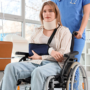 A person with a neck brace and arm sling in a wheelchair, present car accident.