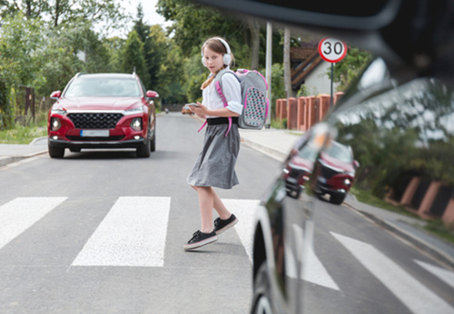 Child crossing a crosswalk as a red SUV approaches, illustrating the dangers of a pedestrian accident