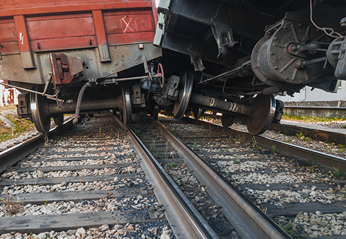 Close-up of a freight train derailment with derailed wheels lying across the train tracks and ballast