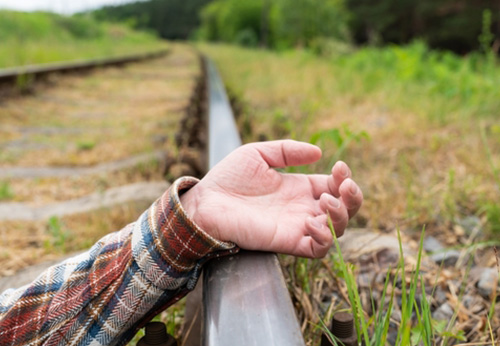 Close-up of a person's hand lying near a train track, illustrating the legal framework for train accidents in Arkansas